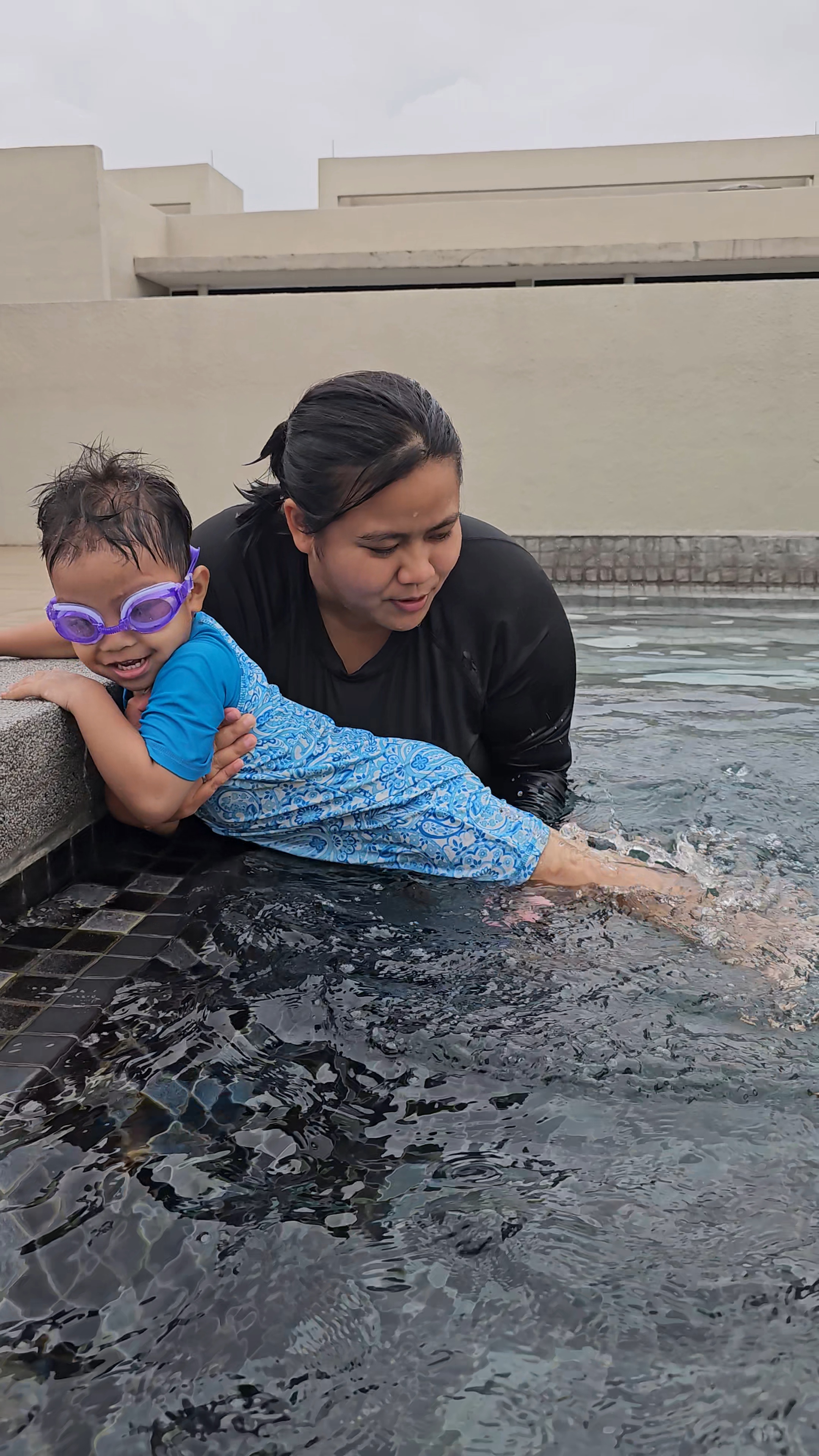Coach Khai guiding a young student at the pool edge